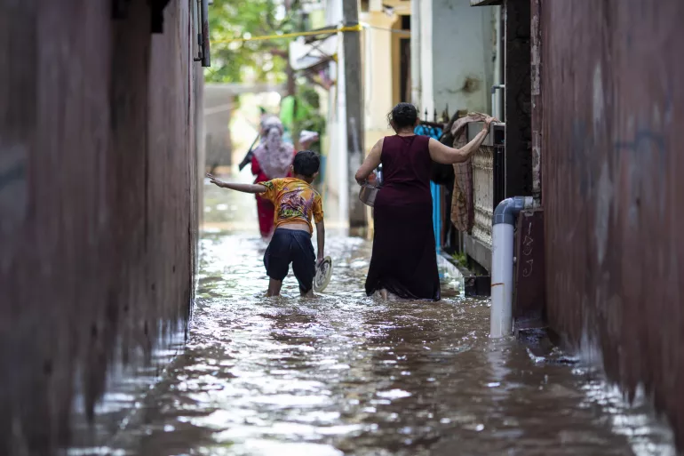 COP 30: Direito da criança nas decisões sobre crise climática 1 Em 21 De Fevereiro De 2021, Um Menino E Sua Mãe Caminham Através Das Águas Em Uma Área Afetada Por Enchentes No Leste De Jacarta, Indonésia.